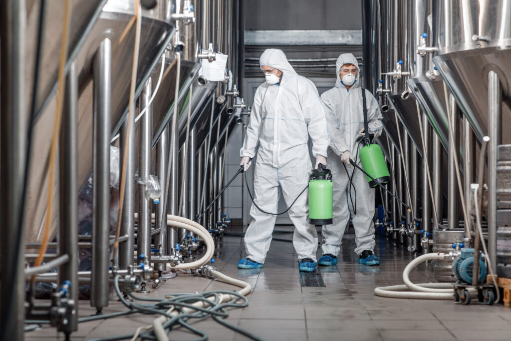 Reinigungsteam in Schutzanzügen bei der Industriereinigung einer Produktionsanlage