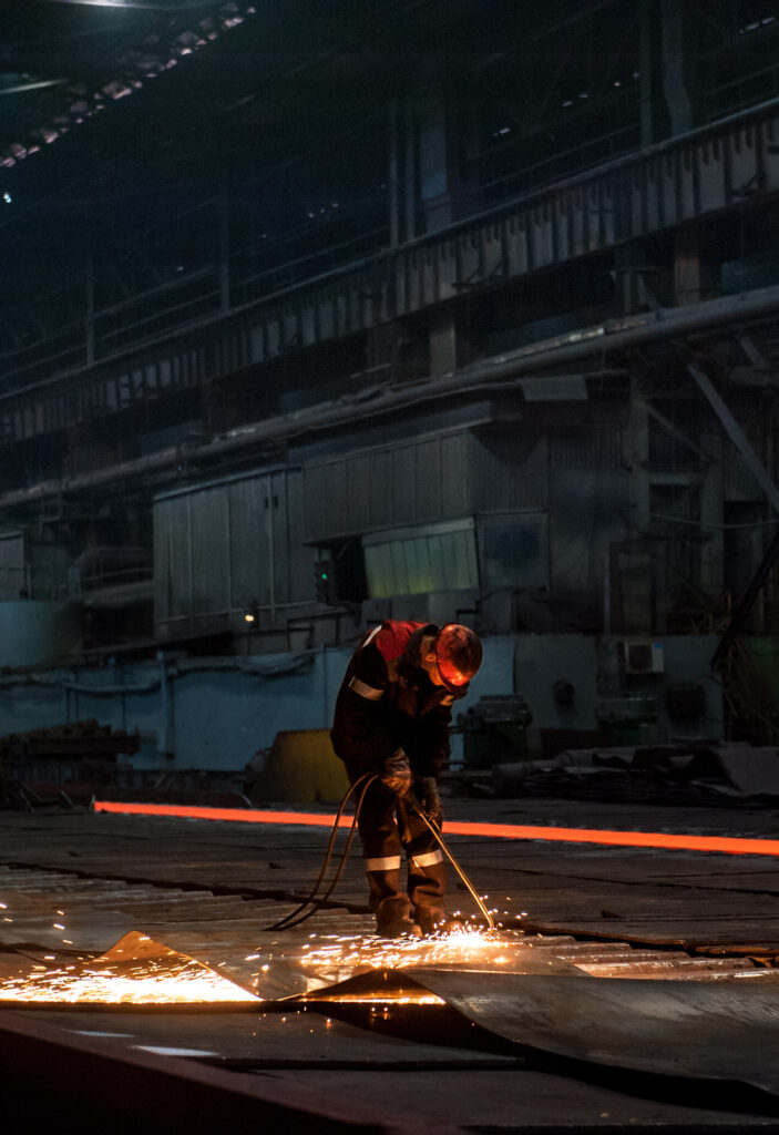 Schweißer mit Schutzhelm bei Schweißarbeiten in einer Industriehalle