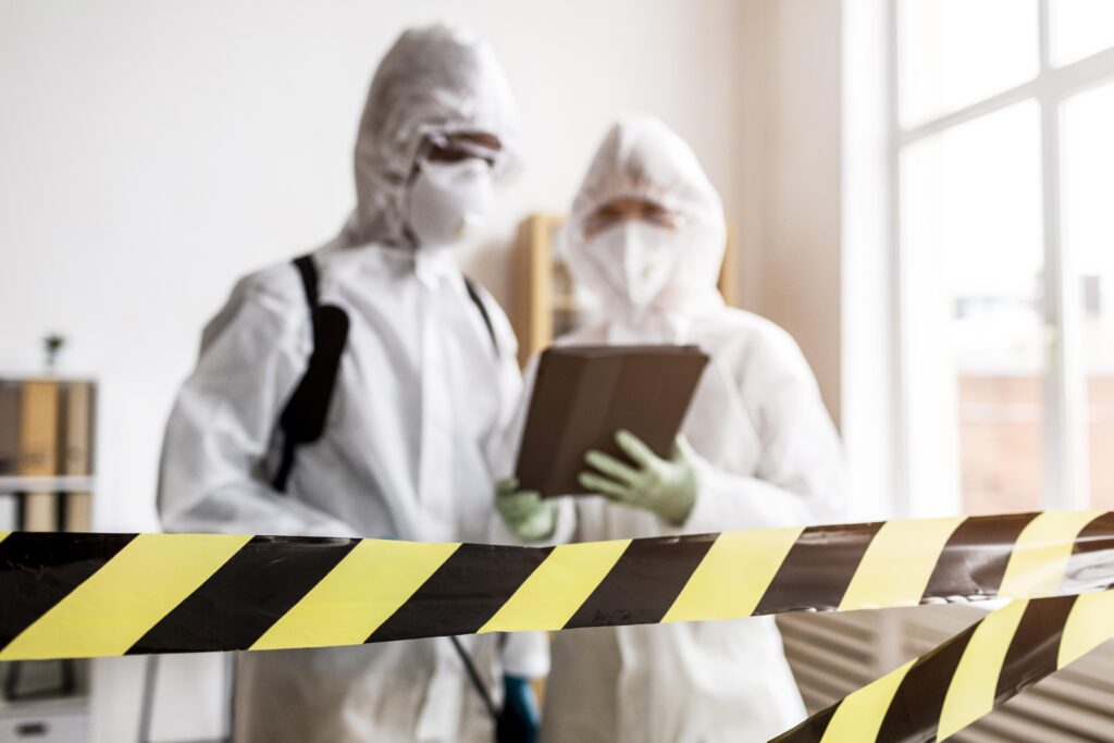Sanierungsteam in Schutzkleidung hinter einer Absperrung bei der Schadstoffsanierung